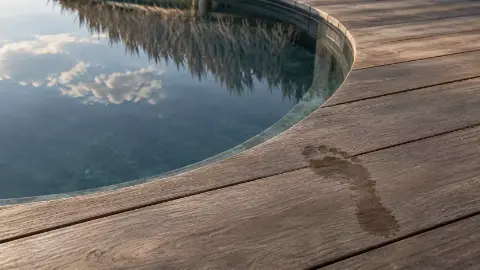 Une empreinte mouillée sur le bois, près du bord arrondi d'un jacuzzi.