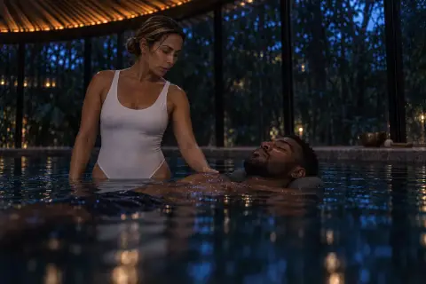 Una terapeuta acompaña una sesión de flotación en la piscina de un spa, de noche.